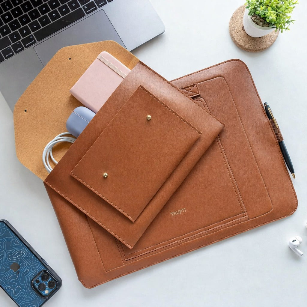 Brown leather laptop sleeve on a white surface with a laptop and phone.